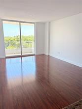 An empty room with dark wood flooring and a sliding glass door leading to a balcony — 700 E Boynton Beach Boulevard # 510, Boynton Beach FL 33435, BOYNTON BEACH, FL