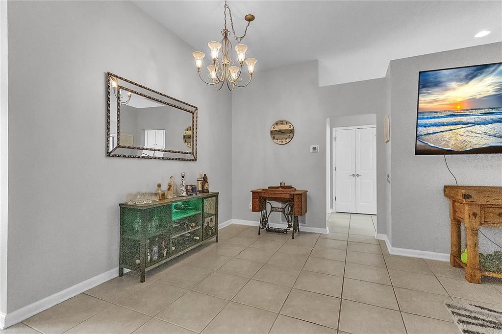 A dining room features a wooden table, four upholstered chairs, a chandelier, and a mirror — 32 SHINNECOCK DRIVE, PALM COAST, FL