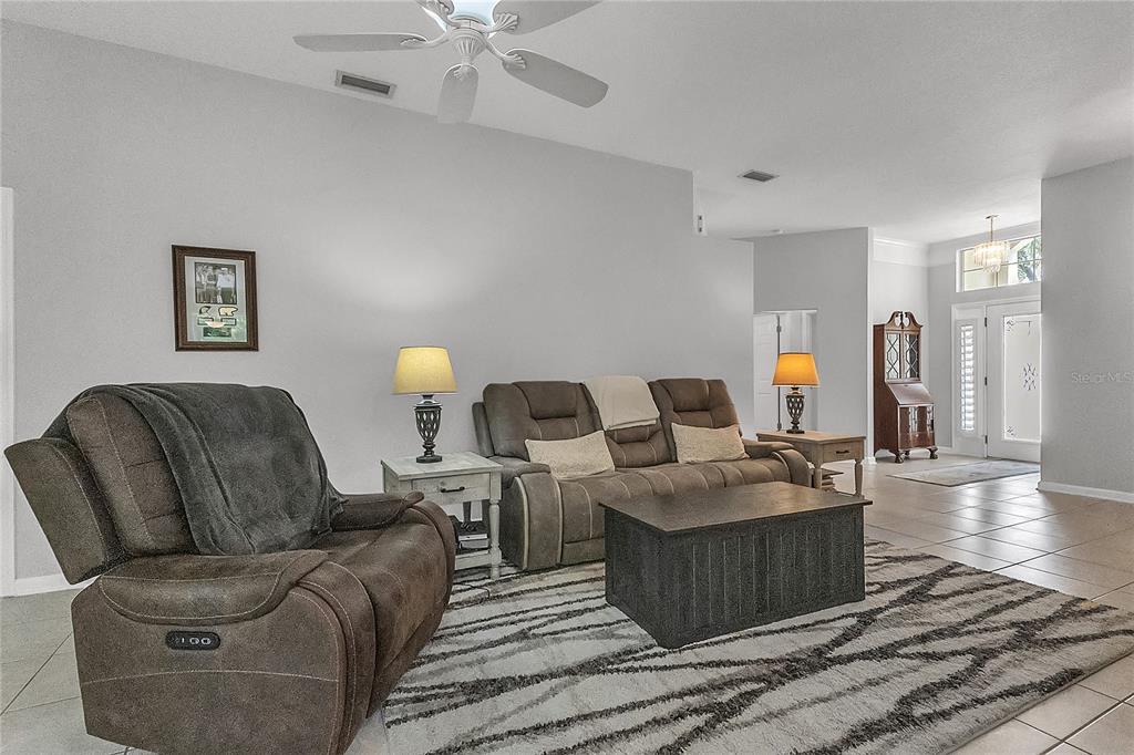 A living room features a gray sofa, a matching recliner, and a patterned area rug — 32 SHINNECOCK DRIVE, PALM COAST, FL