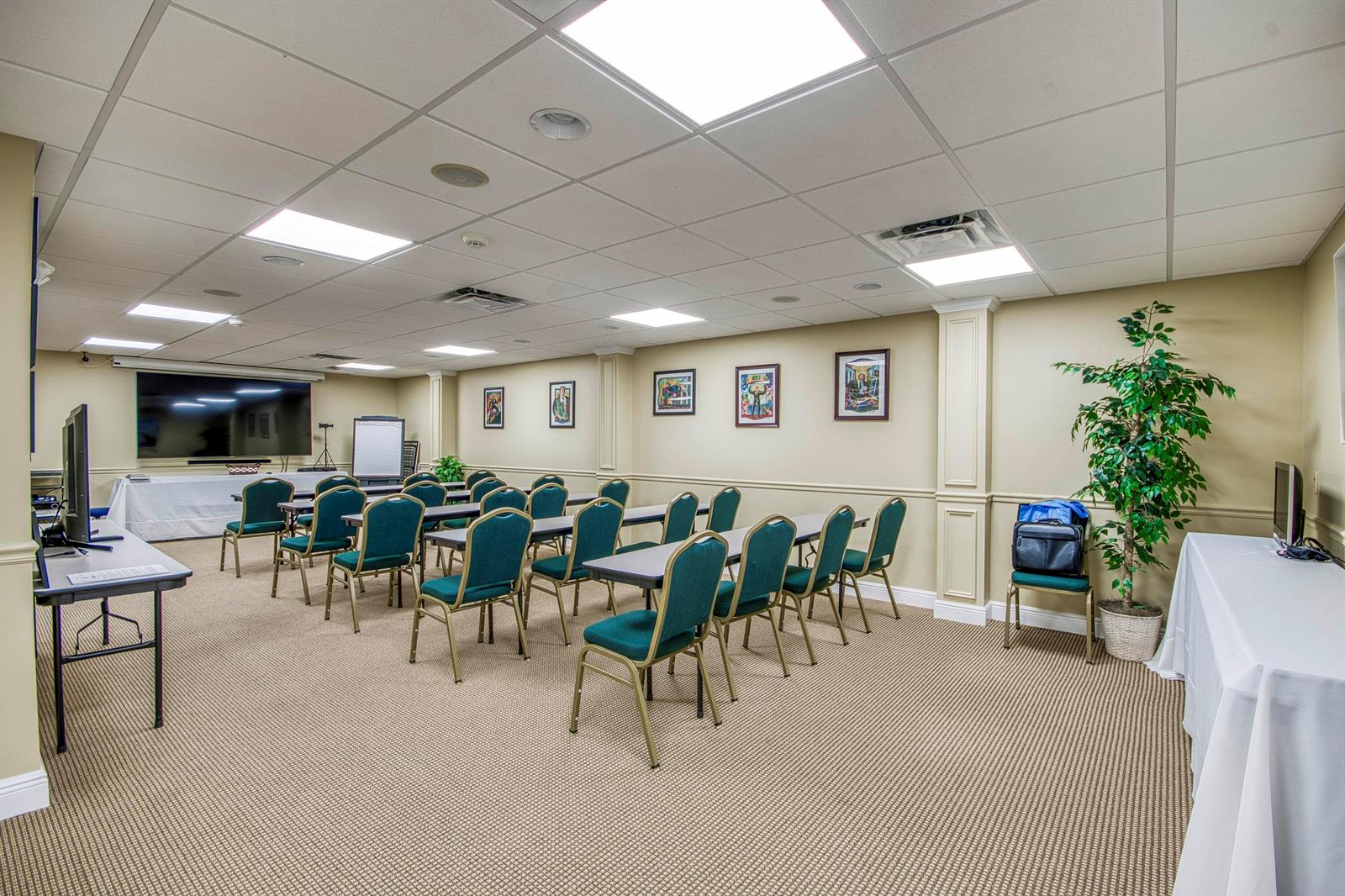 A conference room features rows of chairs, tables, a large screen, and beige walls — 2684 SE Willoughby Boulevard, Stuart FL 34994, STUART, FL