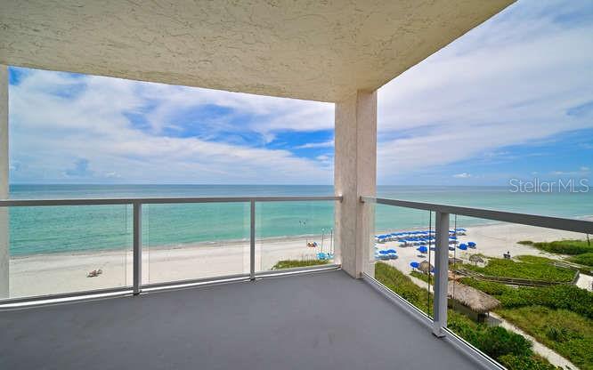 A covered balcony with a glass railing overlooks a sandy beach and the ocean — 2425 GULF OF MEXICO DRIVE UNIT 7F, LONGBOAT KEY, FL