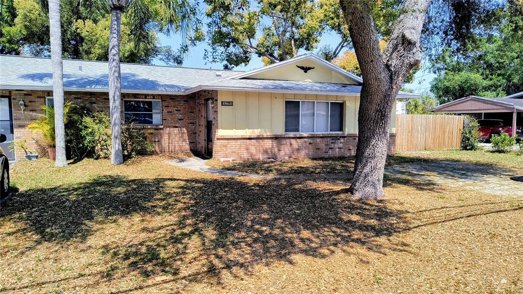 A single-story brick and siding house with a front yard and a detached carport — 10861 126TH AVENUE, LARGO, FL