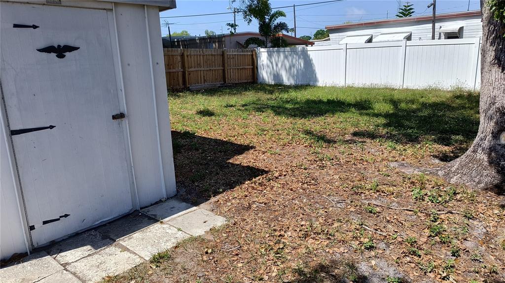 A white shed stands in a backyard with a wooden fence and a white vinyl fence — 10861 126TH AVENUE, LARGO, FL
