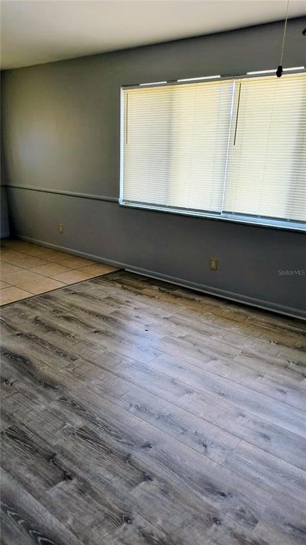A room features gray walls, wood-look flooring, a tiled corner, and horizontal window blinds — 10861 126TH AVENUE, LARGO, FL