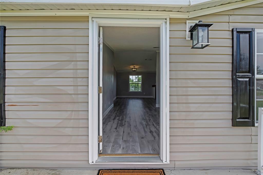 An open front door reveals a view into a living area with wood-look flooring — 36125 WHITE FIR WAY, DADE CITY, FL