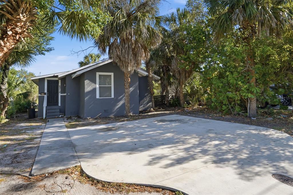 A gray house with a concrete driveway and palm trees stands under a blue sky — 2717 13TH AVENUE S, ST PETERSBURG, FL