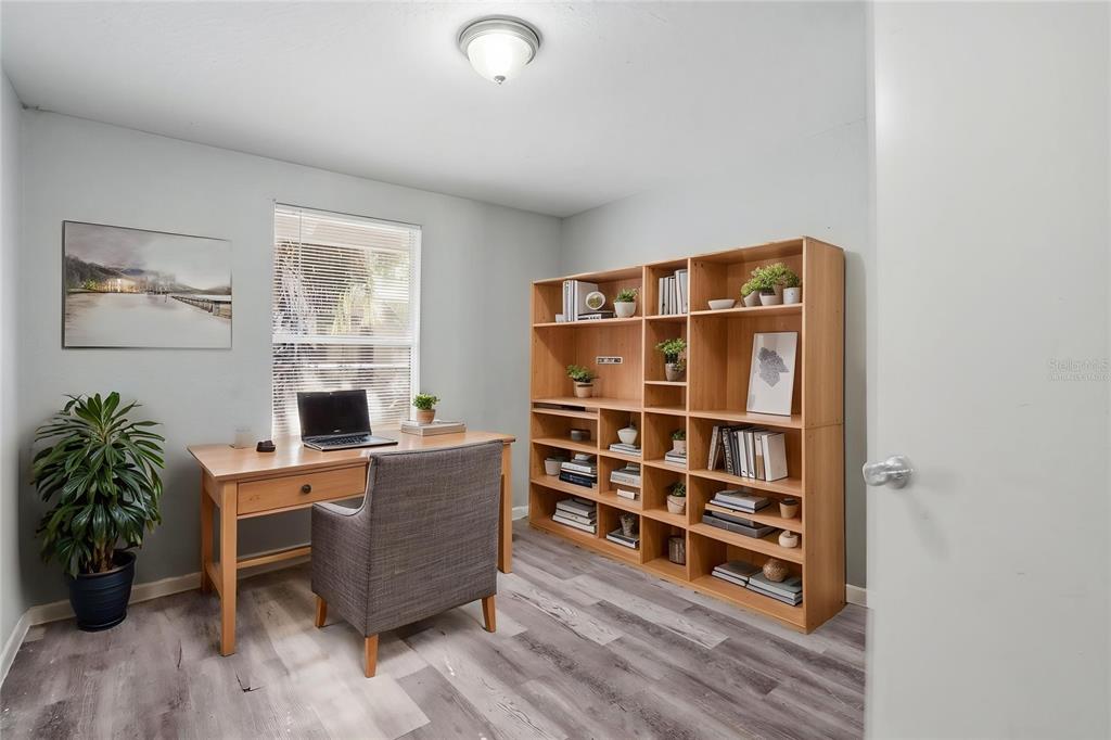 A home office features a wooden desk, a large bookshelf, and light gray wood-look flooring — 2717 13TH AVENUE S, ST PETERSBURG, FL
