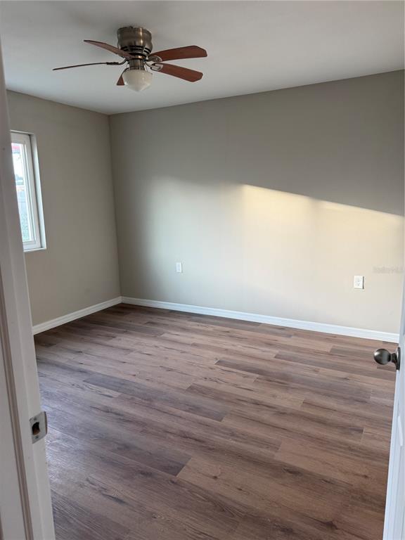An empty bedroom features light gray walls, wood-look flooring, a ceiling fan, and a window — 39132 COUNTY ROAD 54 UNIT 2018, ZEPHYRHILLS, FL