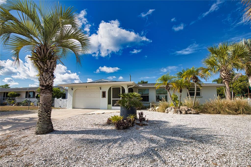 A single-story house with a gravel front yard, palm trees, and a white garage door — 1 CAROLL CIRCLE, ENGLEWOOD, FL