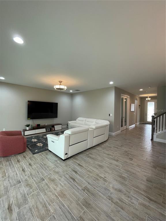 A living room features a white sectional sofa, a red armchair, and wood-look tile flooring — 18036 RAMBLE ON WAY, LAND O LAKES, FL