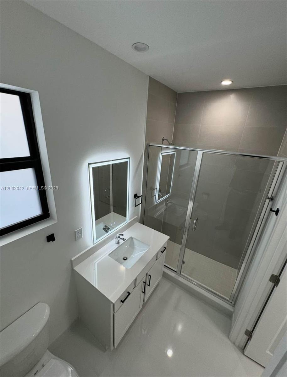 A modern bathroom features a white vanity, a glass-enclosed shower, and a backlit mirror — 14429 SW 19th St # 1, Miami FL 33175, MIAMI, FL