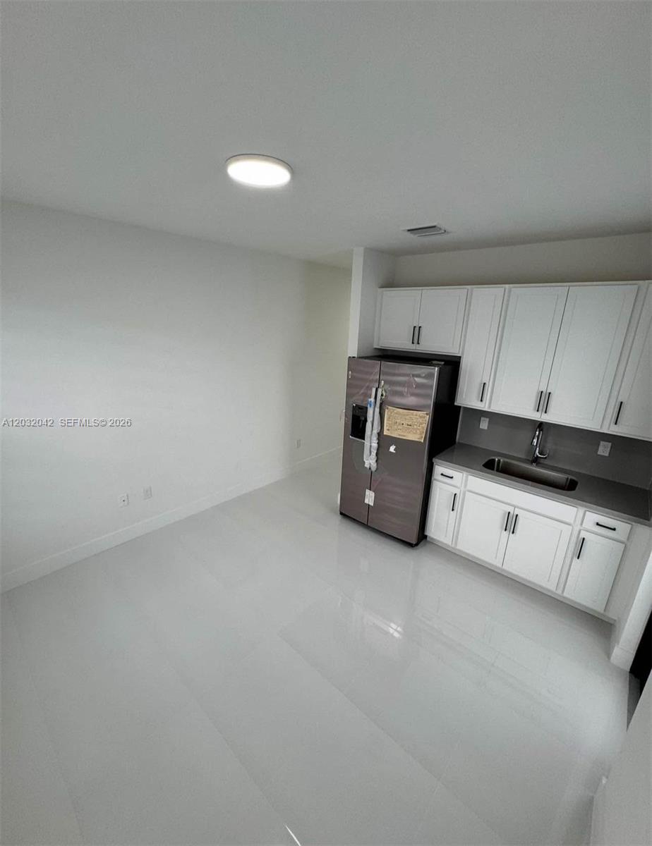 A kitchen area features white cabinets, a stainless steel refrigerator, and light-colored tile flooring — 14429 SW 19th St # 1, Miami FL 33175, MIAMI, FL