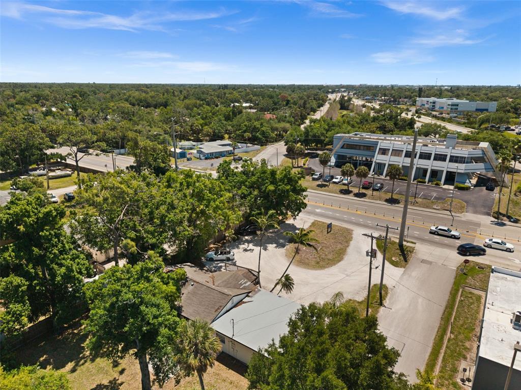 An aerial view shows a residential property with a driveway next to a commercial building — 109 LAUREL ROAD E, NOKOMIS, FL
