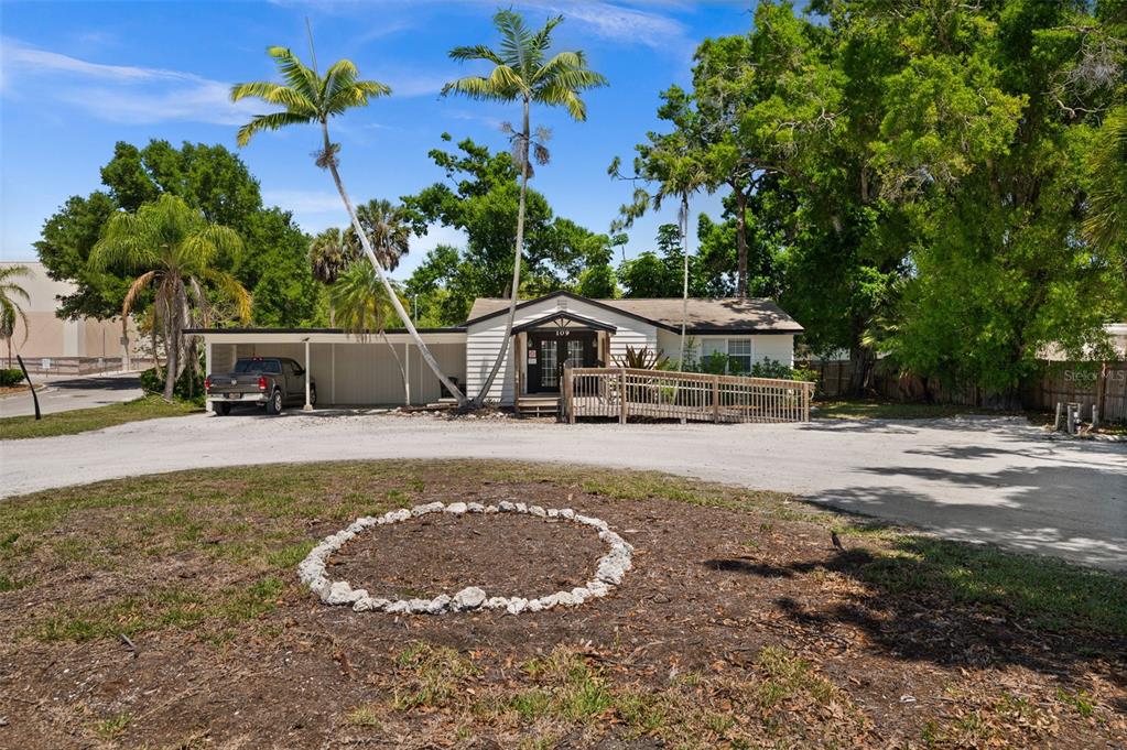 A single-story building with a carport, a wooden wheelchair ramp, and two tall palm trees — 109 LAUREL ROAD E, NOKOMIS, FL