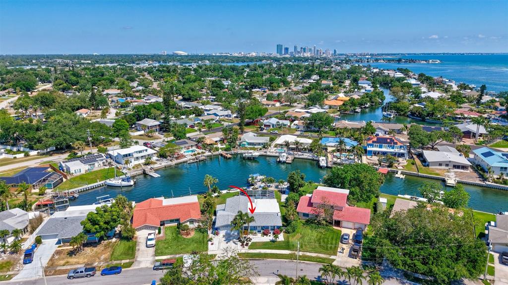 An aerial view shows a waterfront house with a screened pool, sandy patio, and dock — 563 LEWIS BOULEVARD SE, ST PETERSBURG, FL