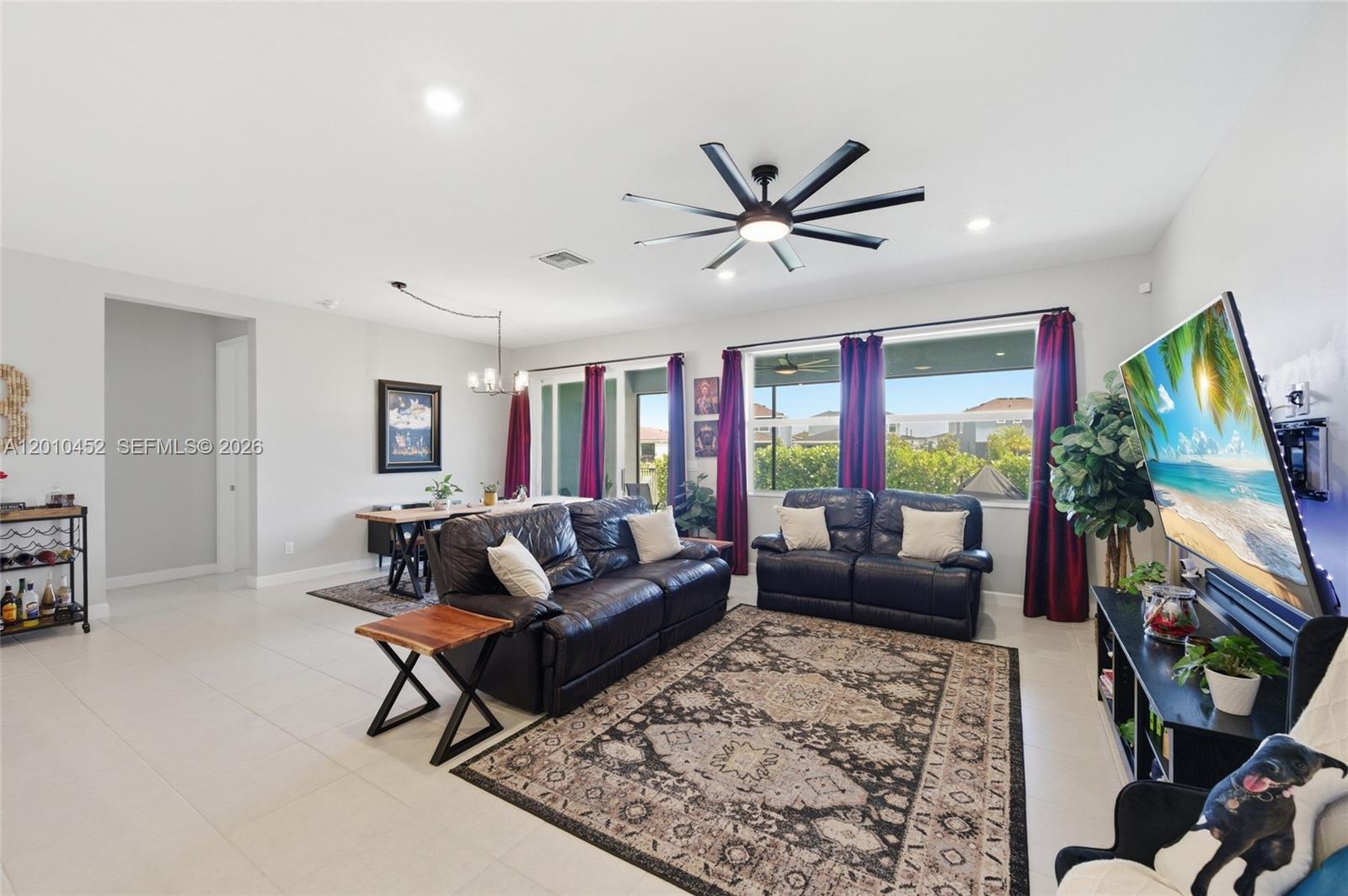 A living room features dark leather sofas, a patterned area rug, and a dining area — 1902 Wandering Willow Way, Loxahatchee FL 33470, LOXAHATCHEE, FL