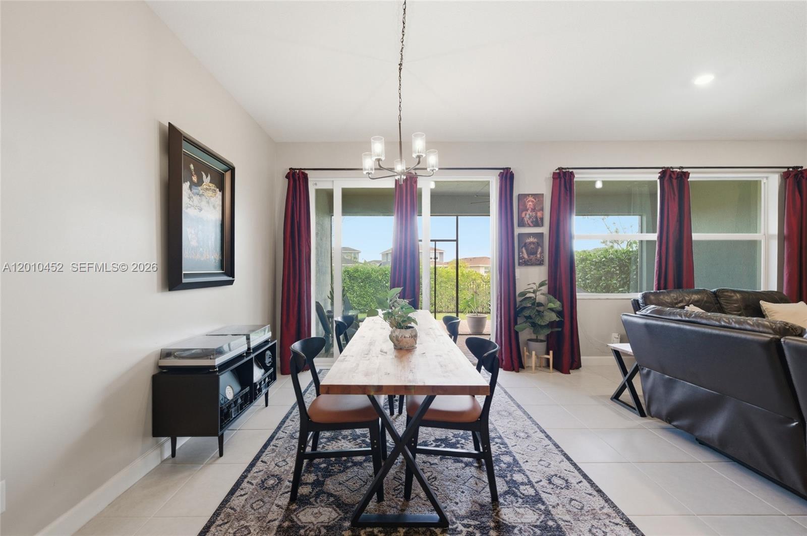 A dining room features a wooden table, black chairs, a patterned rug, and red curtains — 1902 Wandering Willow Way, Loxahatchee FL 33470, LOXAHATCHEE, FL