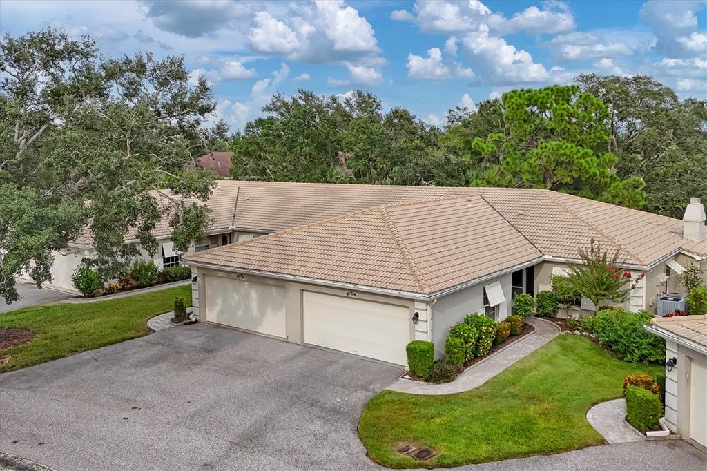 An exterior view of a single-story house with a two-car garage and tile roof — 3244 RINGWOOD MEADOW UNIT 77, SARASOTA, FL