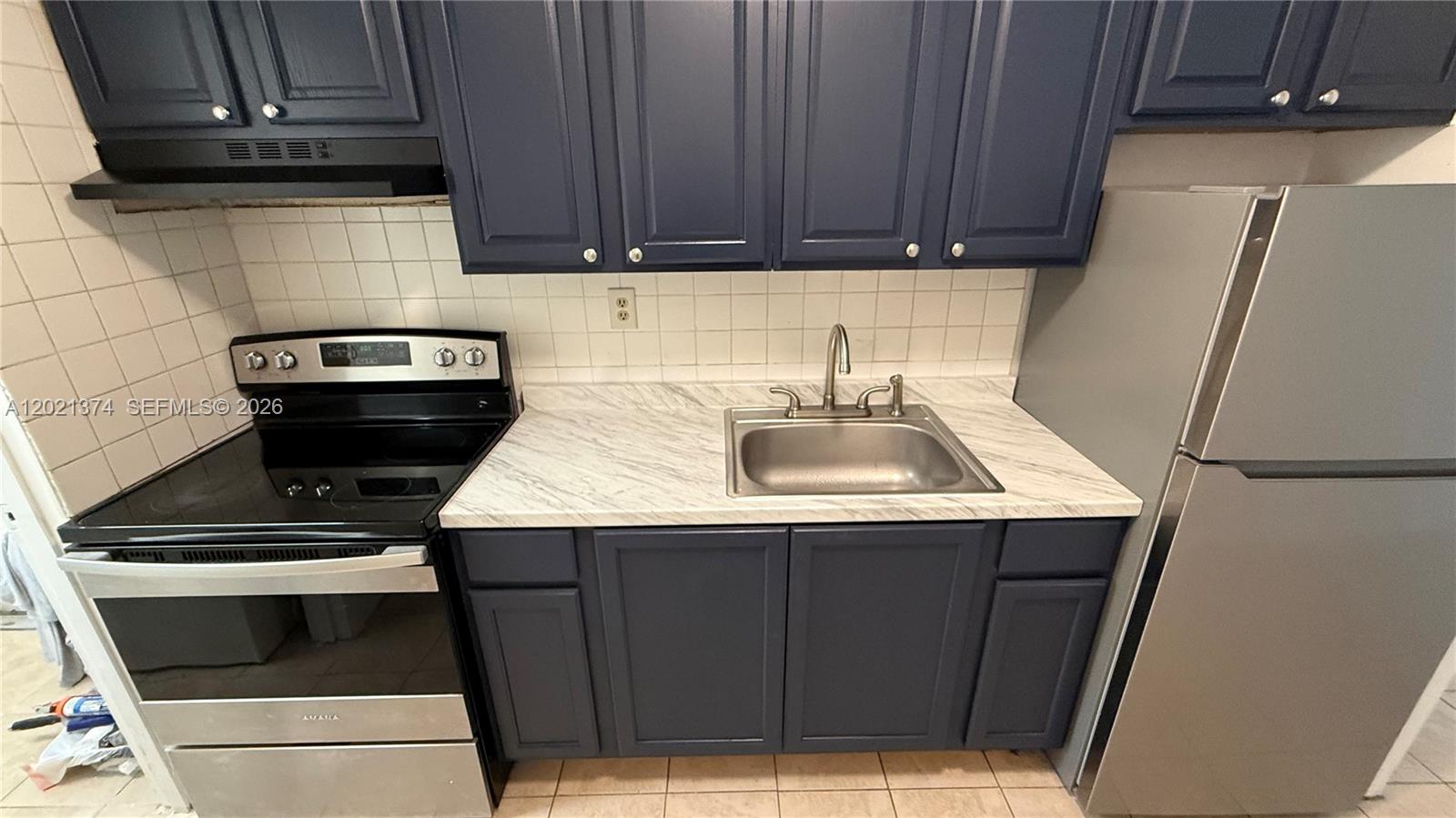 A kitchen features dark blue cabinets, a stainless steel stove, a sink, and marble-patterned countertops — 4940 SW 28th Ter, Dania Beach FL 33312, DANIA BEACH, FL