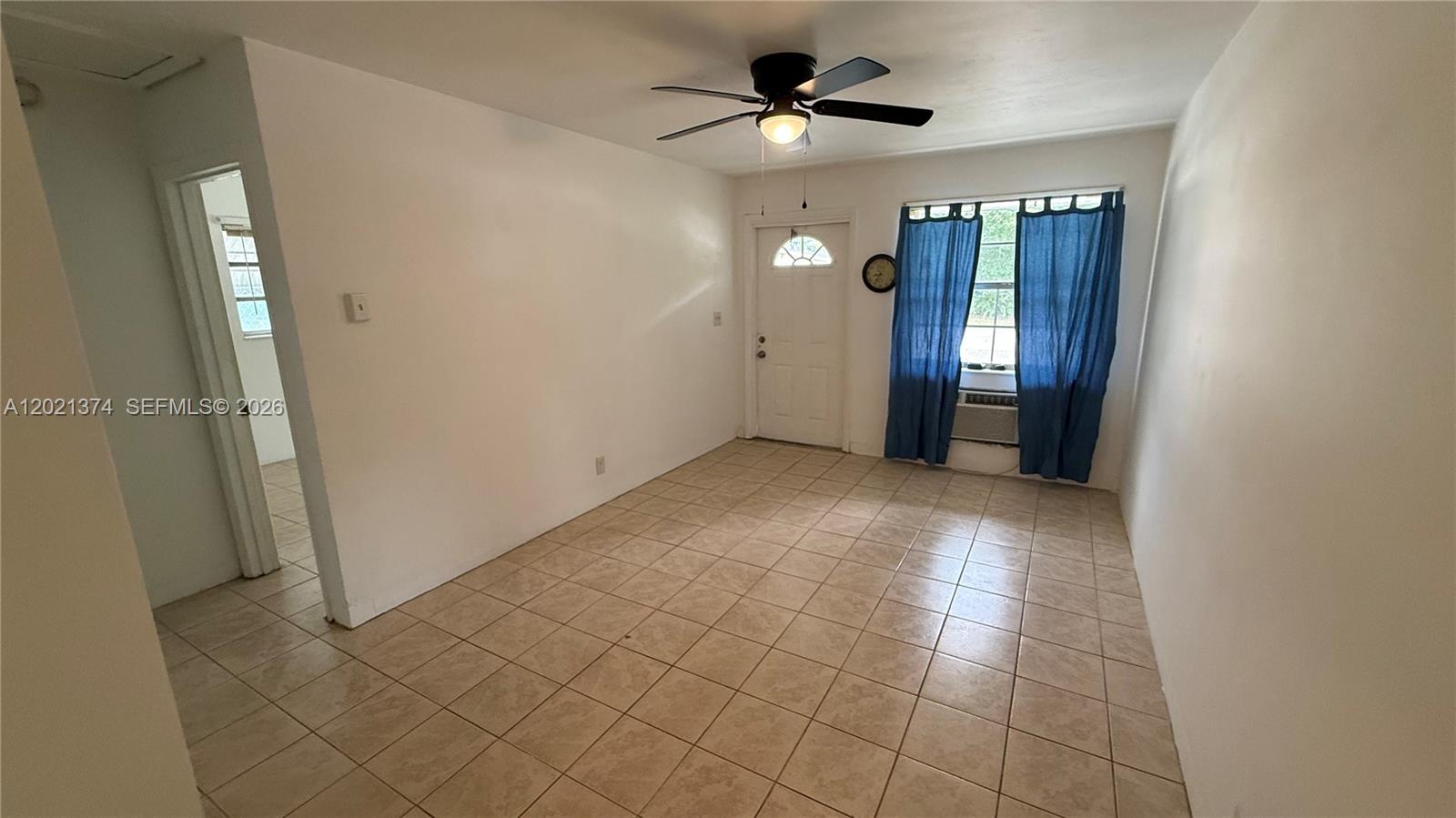 A room with white walls, tan tile flooring, a ceiling fan, and blue curtains — 4940 SW 28th Ter, Dania Beach FL 33312, DANIA BEACH, FL