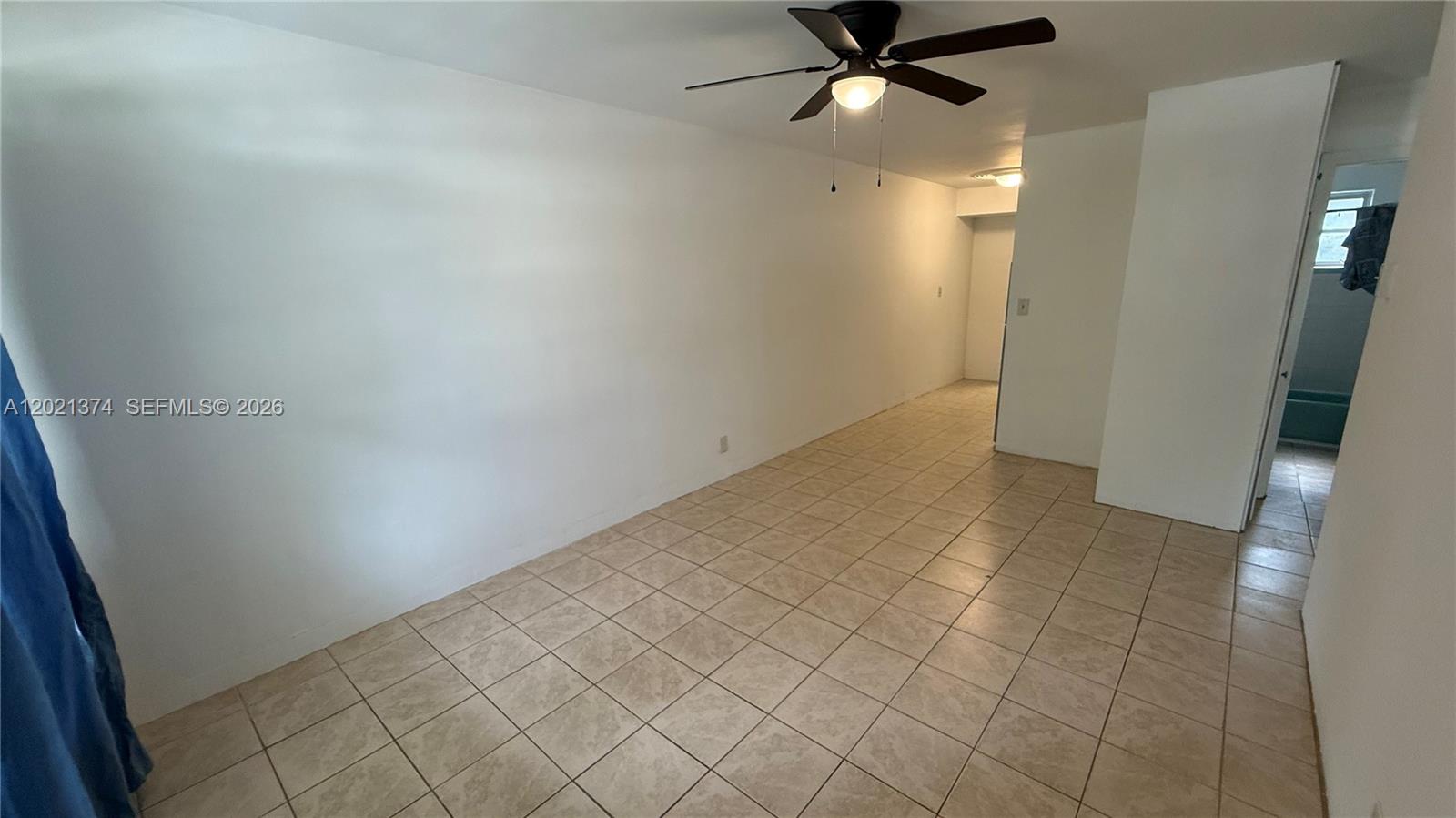 An empty room features white walls, beige tile flooring, and a ceiling fan — 4940 SW 28th Ter, Dania Beach FL 33312, DANIA BEACH, FL