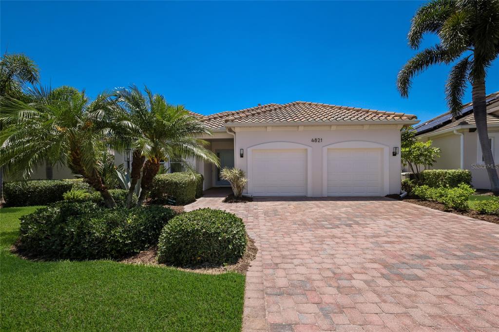 A single-story house with a two-car garage, paver driveway, and palm trees in the front — 4821 ROYAL DORNOCH CIRCLE, BRADENTON, FL