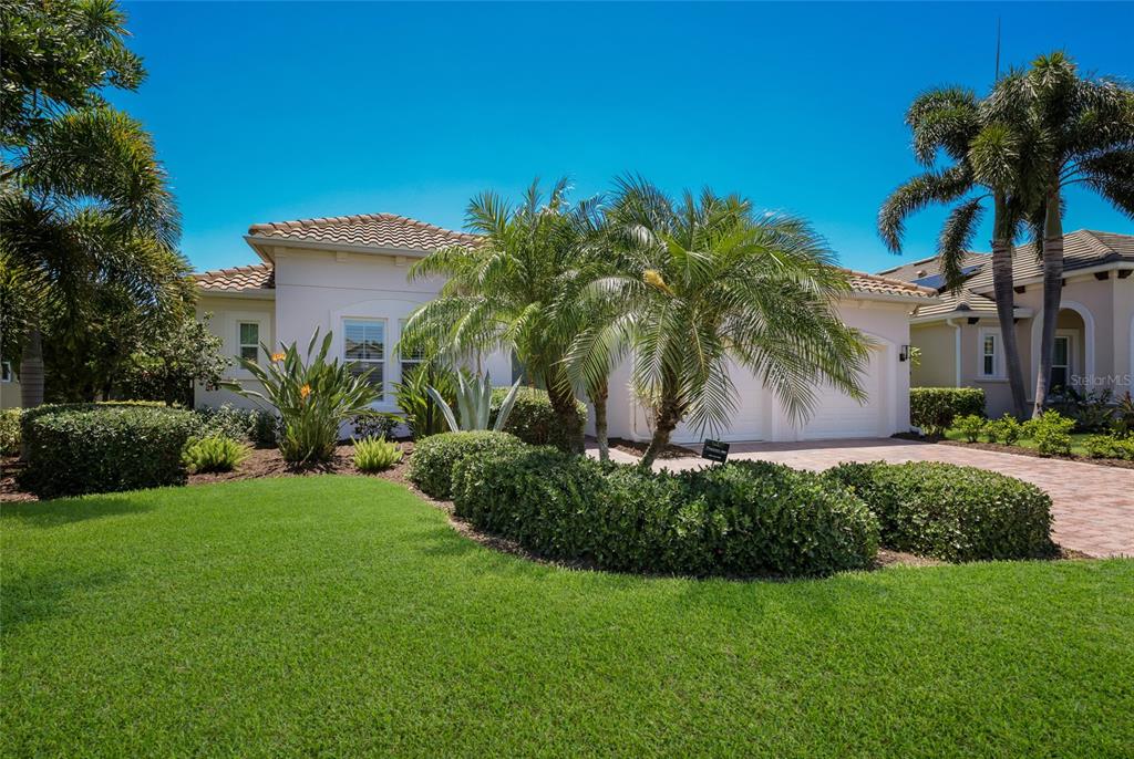 A single-story house with a tiled roof, palm trees, and a manicured lawn — 4821 ROYAL DORNOCH CIRCLE, BRADENTON, FL