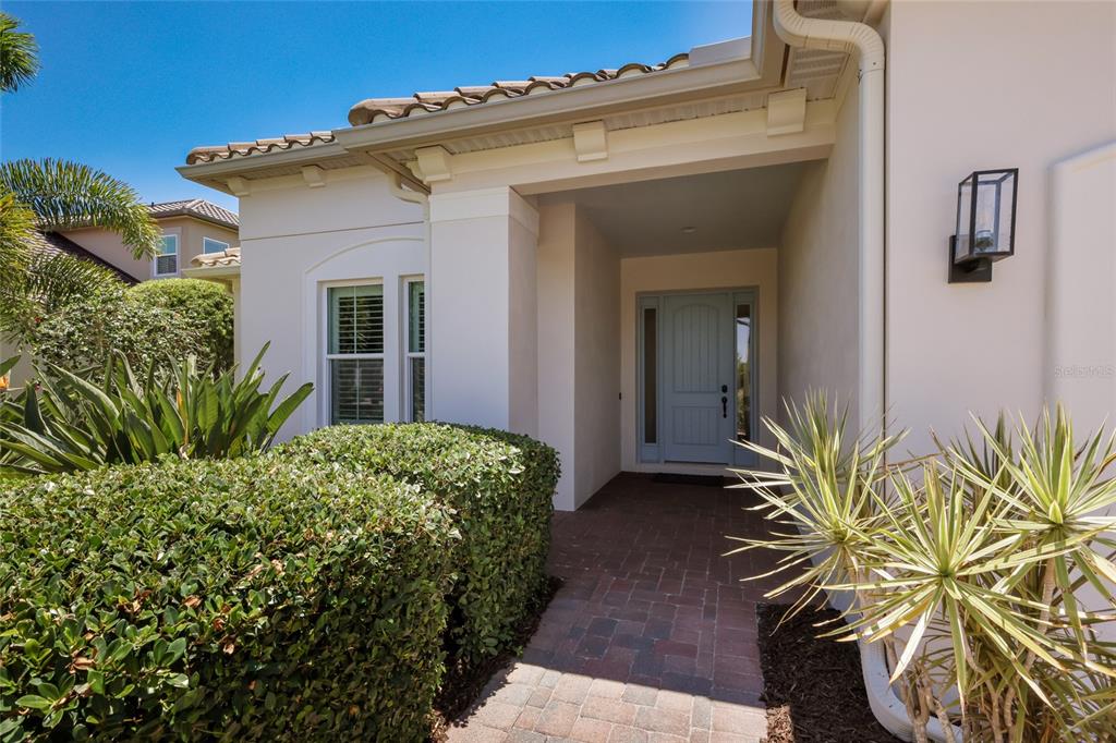 The exterior view shows a house entrance with a paved walkway, landscaping, and light-colored siding — 4821 ROYAL DORNOCH CIRCLE, BRADENTON, FL