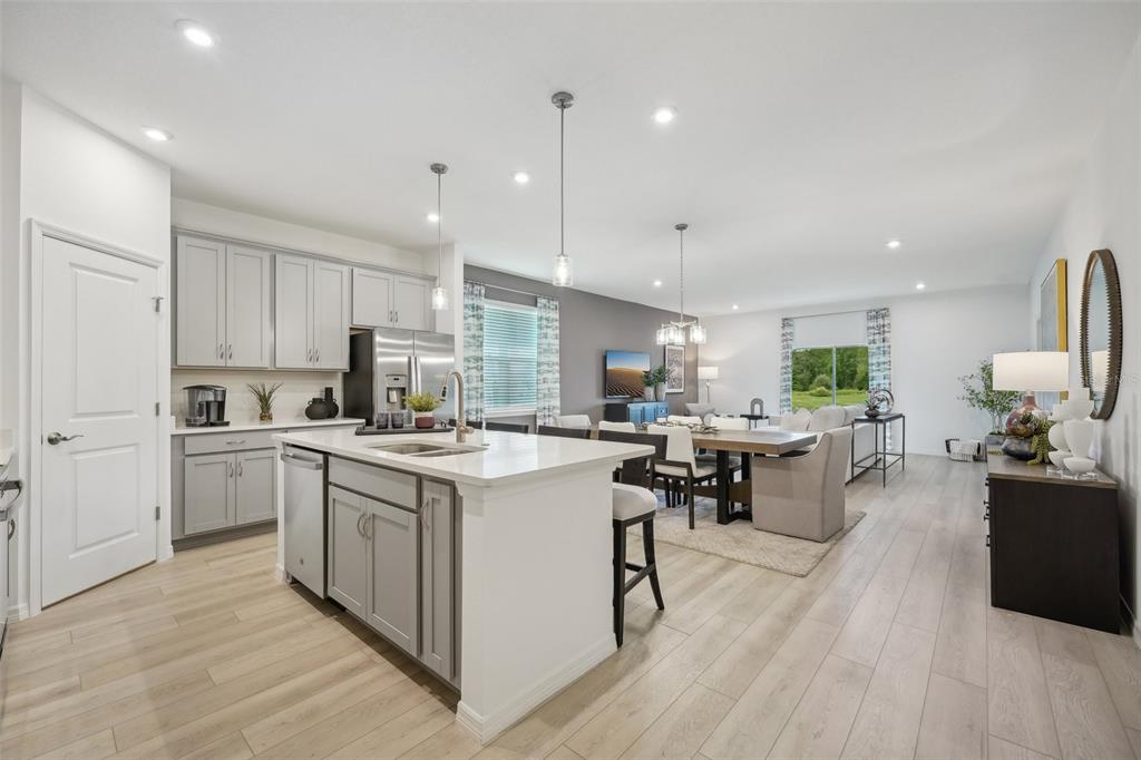 An open-concept kitchen and dining area features gray cabinetry, a white island, and light flooring — 12831 TROVITA DRIVE, GRAND ISLAND, FL