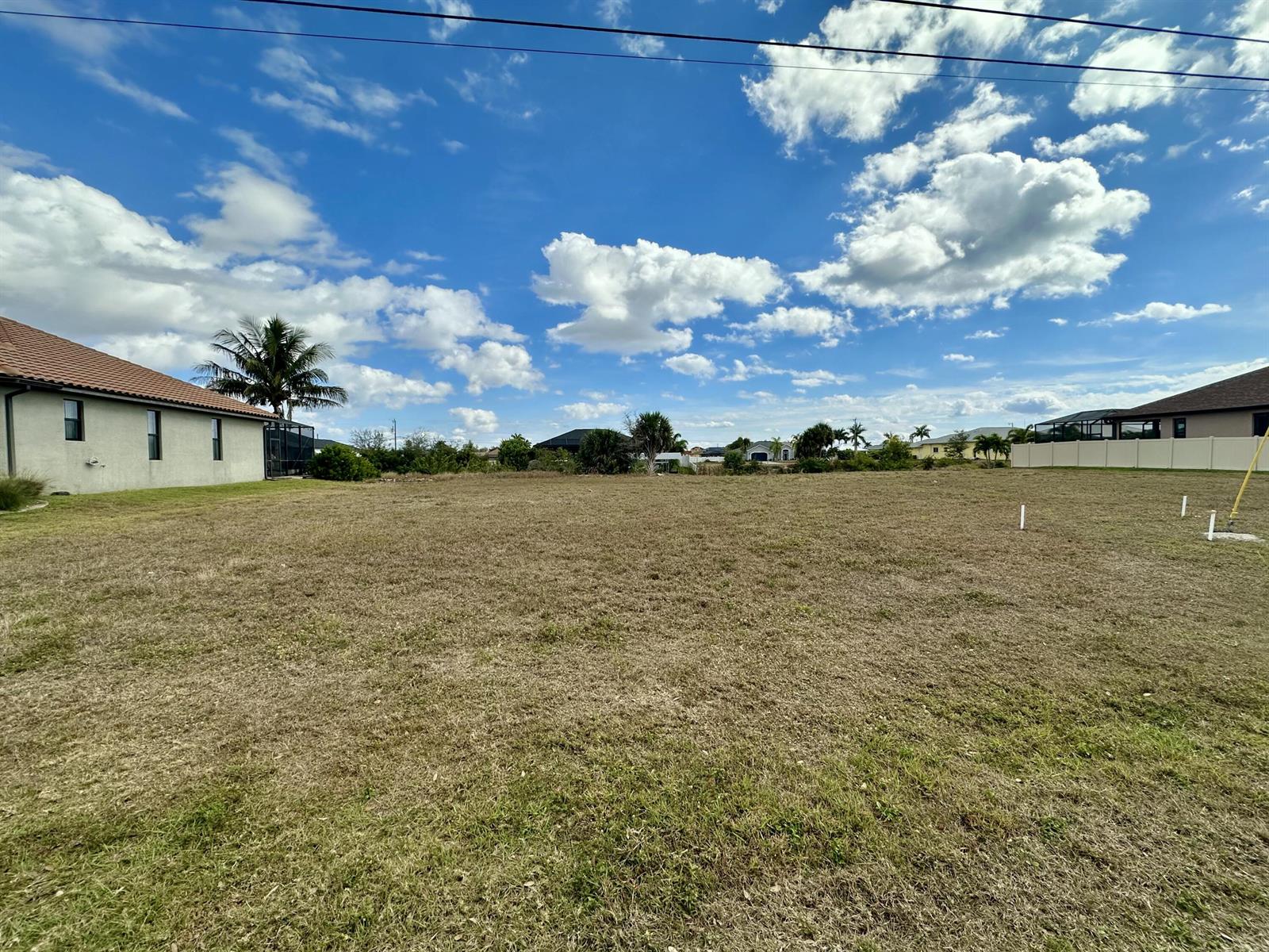 A large, flat, grassy vacant lot under a blue sky with scattered clouds — 2513 Surfside Boulevard, FL 33914, FL