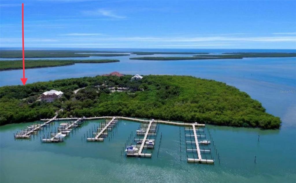 An aerial view shows a private island with a large house, docks, and boat slips — 1260 BLUE HILL CREEK DRIVE, MARCO ISLAND, FL