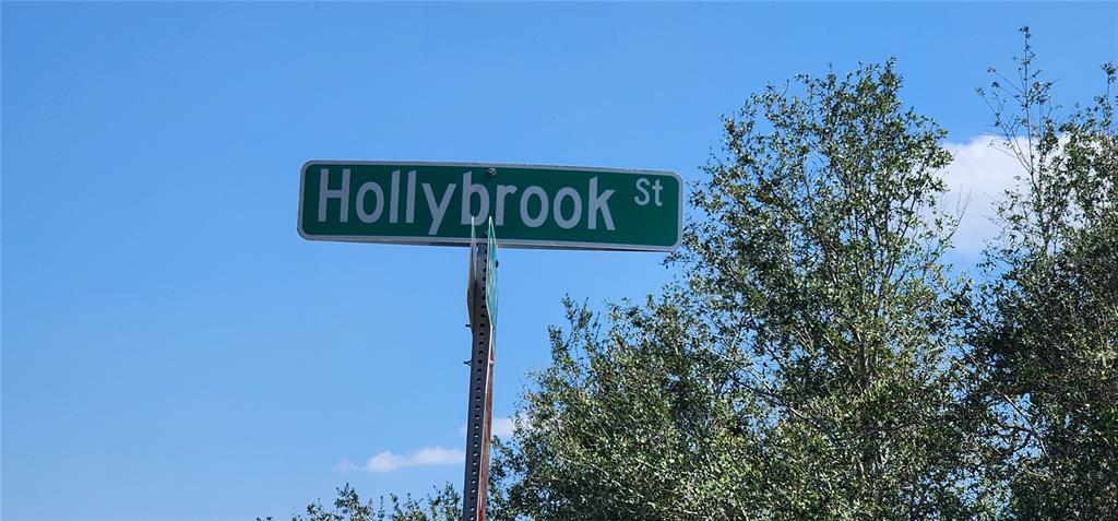 A green street sign labeled Hollybrook St stands against a blue sky next to trees — 4163 HOLLYBROOK STREET, PORT CHARLOTTE, FL