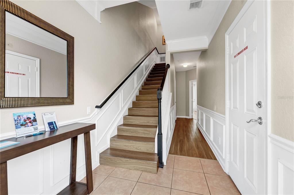 An entryway features a wooden staircase, a console table with a mirror, and tiled flooring — 5064 TIDEVIEW CIRCLE UNIT 82, ORLANDO, FL