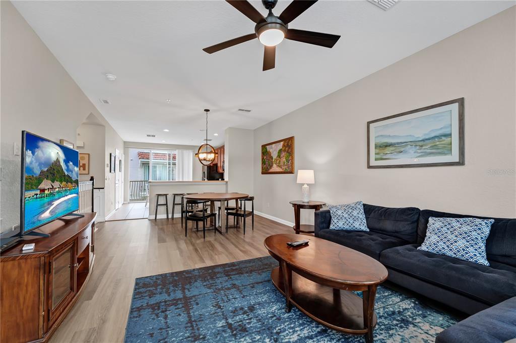 A living room with a dark sofa, wood coffee table, and dining area beyond — 5064 TIDEVIEW CIRCLE UNIT 82, ORLANDO, FL