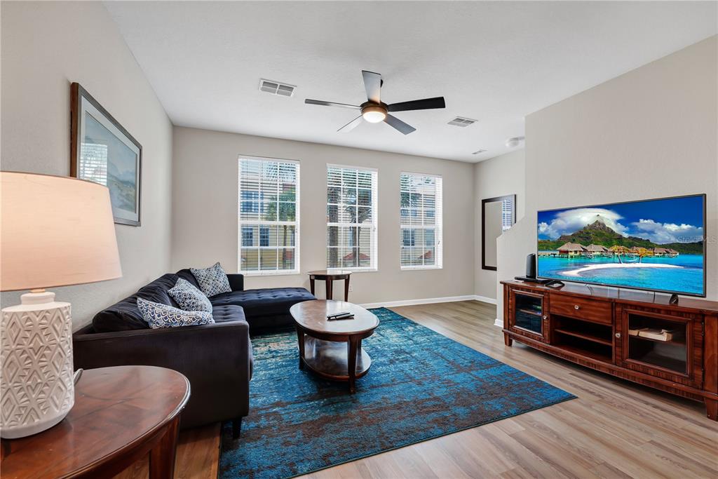 A living room features a dark sectional sofa, a blue area rug, and a television console — 5064 TIDEVIEW CIRCLE UNIT 82, ORLANDO, FL