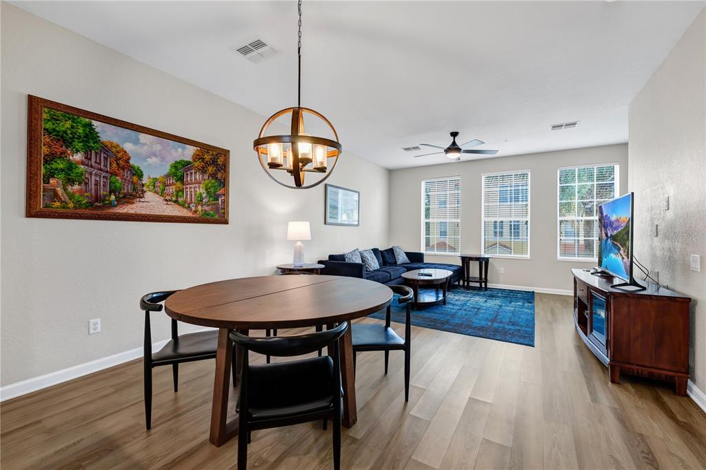 A dining area with a round wooden table sits adjacent to a living room — 5064 TIDEVIEW CIRCLE UNIT 82, ORLANDO, FL