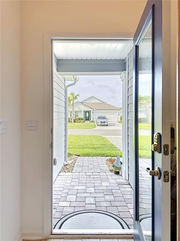 A view from inside a doorway looking out at a paved walkway and a house — 153 GREENWOOD DRIVE, PALM COAST, FL