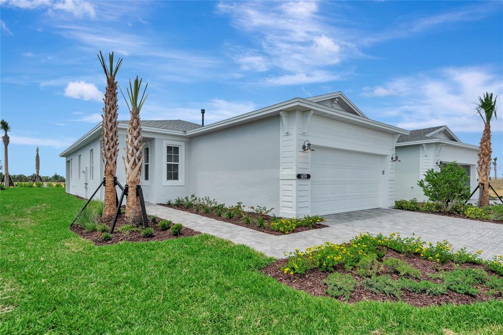A single-story house with a white exterior, a two-car garage, and palm trees in front — 1459 SANTORINI WAY, TAVARES, FL