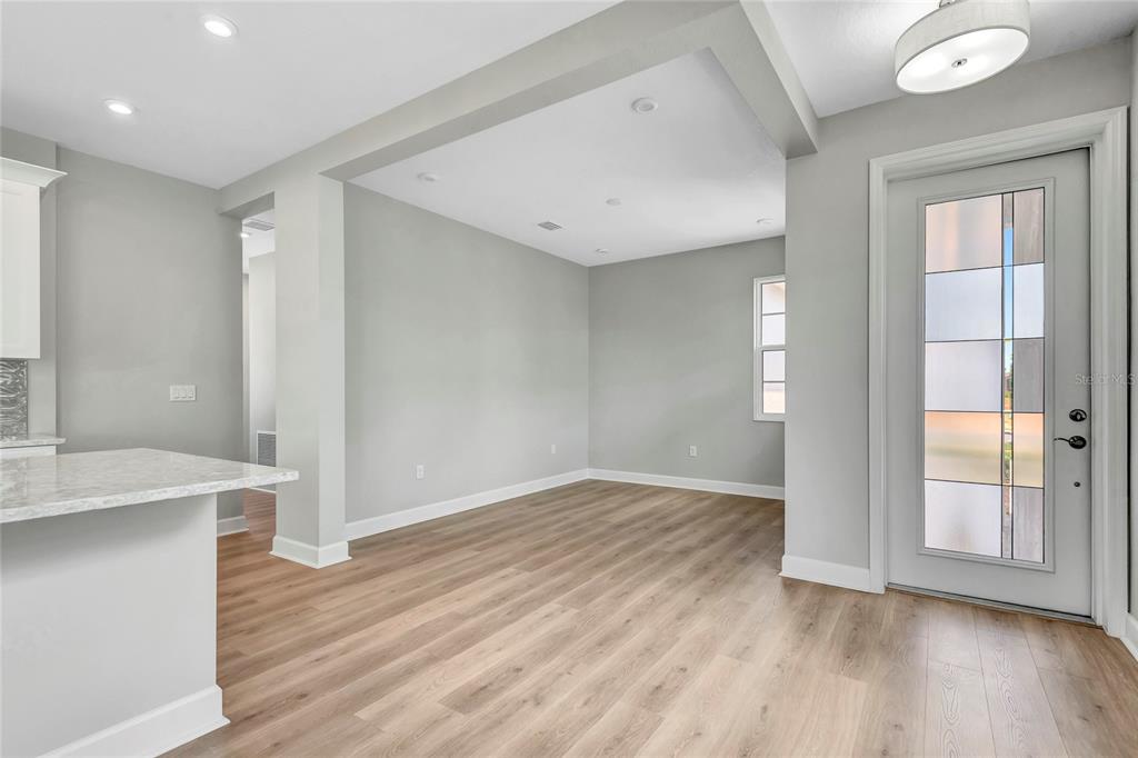 An empty room with light wood flooring, gray walls, recessed lighting, and a glass-paneled door — 1459 SANTORINI WAY, TAVARES, FL