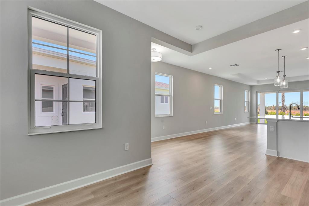 An interior view of a room with light gray walls, wood-look flooring, and multiple windows — 1459 SANTORINI WAY, TAVARES, FL