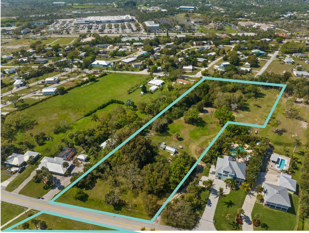 An aerial view shows a large, irregularly shaped vacant lot outlined in blue near houses — SEBASTIAN, FL