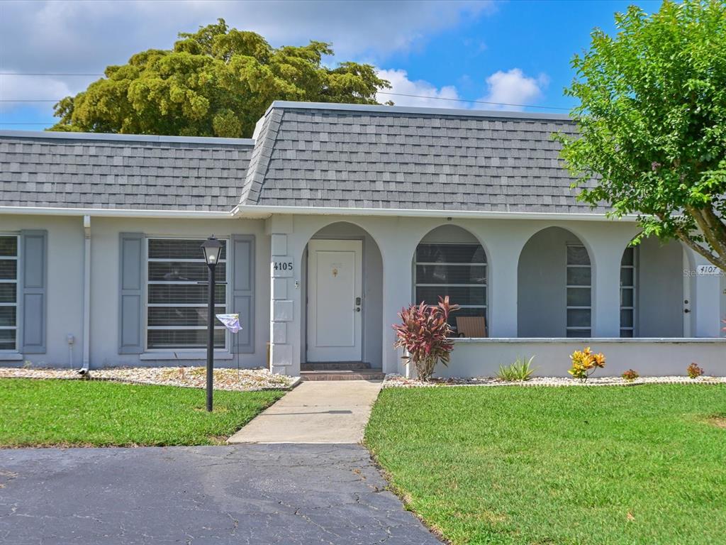 A single-story residential building features a gray shingled roof, arched entryway, and a front lawn — 4105 35TH AVENUE W UNIT 4105, BRADENTON, FL