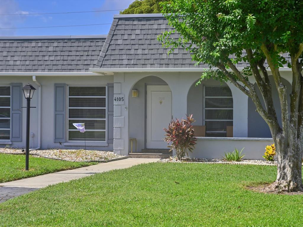 A single-story residential building features a gray shingled roof, arched entryway, and a front lawn — 4105 35TH AVENUE W UNIT 4105, BRADENTON, FL