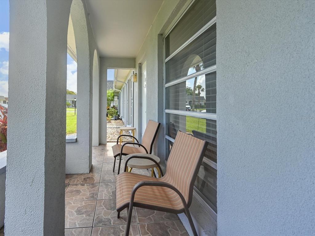 A covered patio features tiled flooring, arched columns, and two outdoor chairs — 4105 35TH AVENUE W UNIT 4105, BRADENTON, FL
