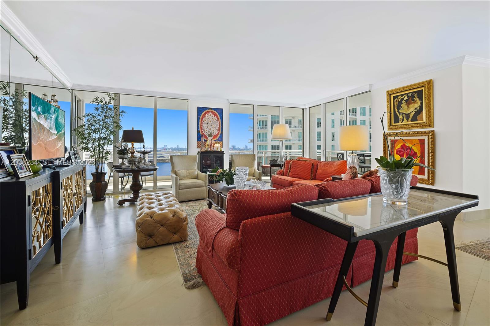 A living room features red sofas, a tufted ottoman, and floor-to-ceiling windows with water views — 901 Brickell Key Blvd # 2408, Miami FL 33131, MIAMI, FL