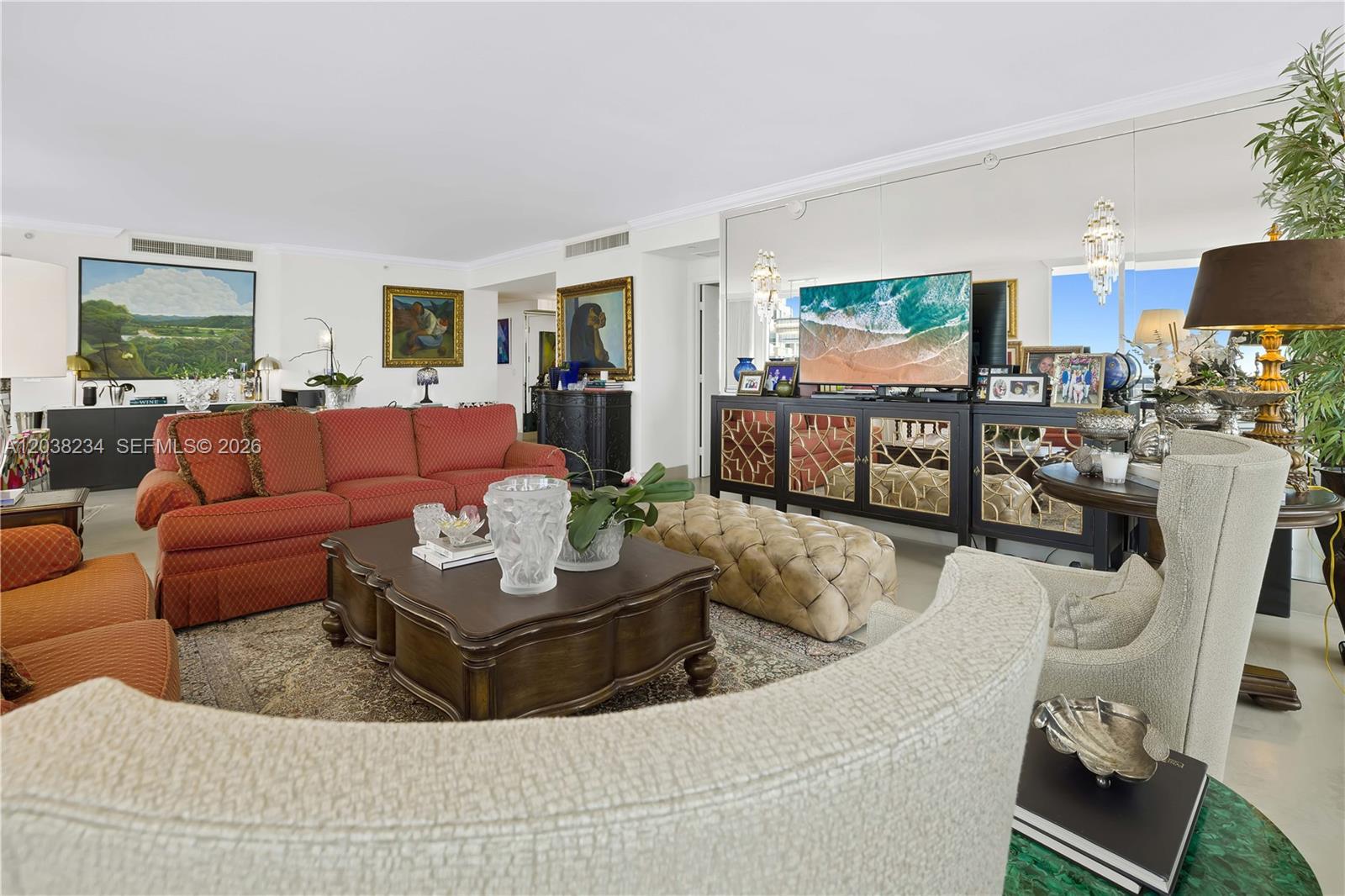 A living room features a red sofa, a tufted ottoman, and a large mirrored wall — 901 Brickell Key Blvd # 2408, Miami FL 33131, MIAMI, FL