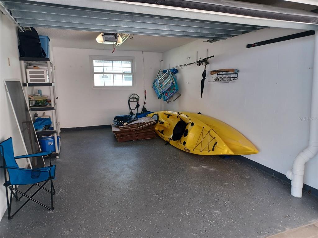 A garage with a gray speckled floor, a yellow kayak, and a blue folding chair — 17960 GULF BOULEVARD UNIT 118, REDINGTON SHORES, FL