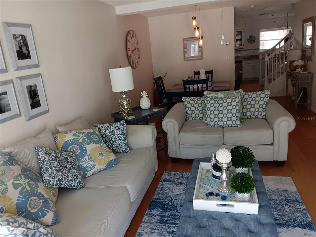 A living room with two sofas, a blue ottoman, and a dining area in the background — 17960 GULF BOULEVARD UNIT 118, REDINGTON SHORES, FL