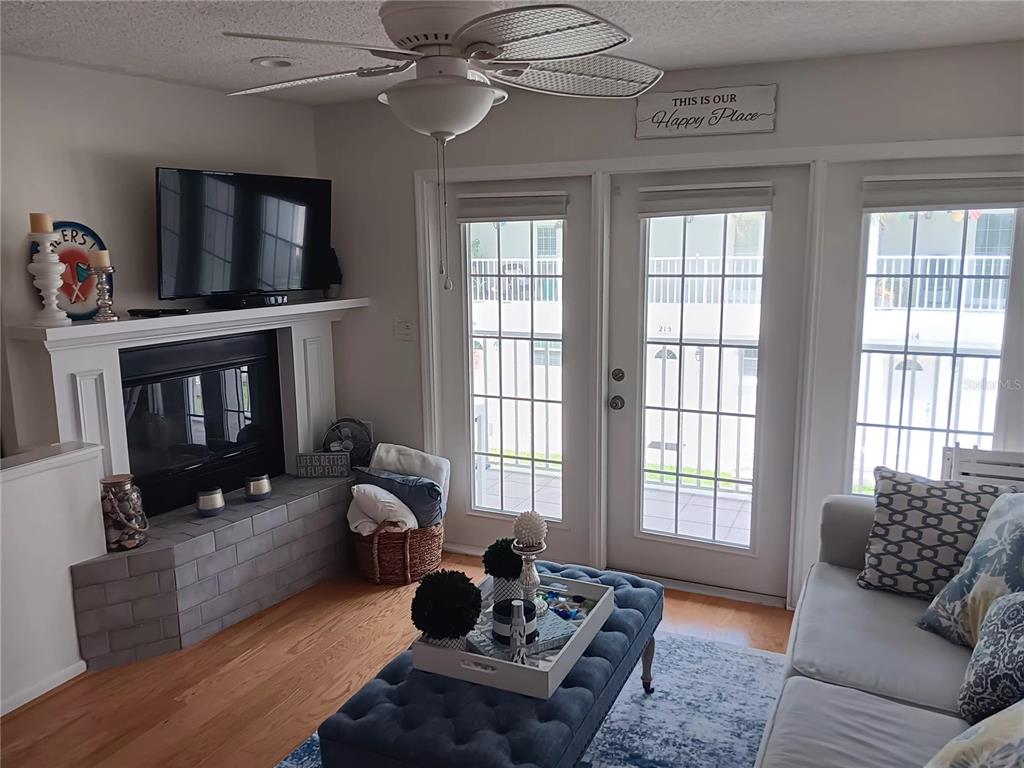 A living room features a fireplace, a blue tufted ottoman, and glass doors to a balcony — 17960 GULF BOULEVARD UNIT 118, REDINGTON SHORES, FL