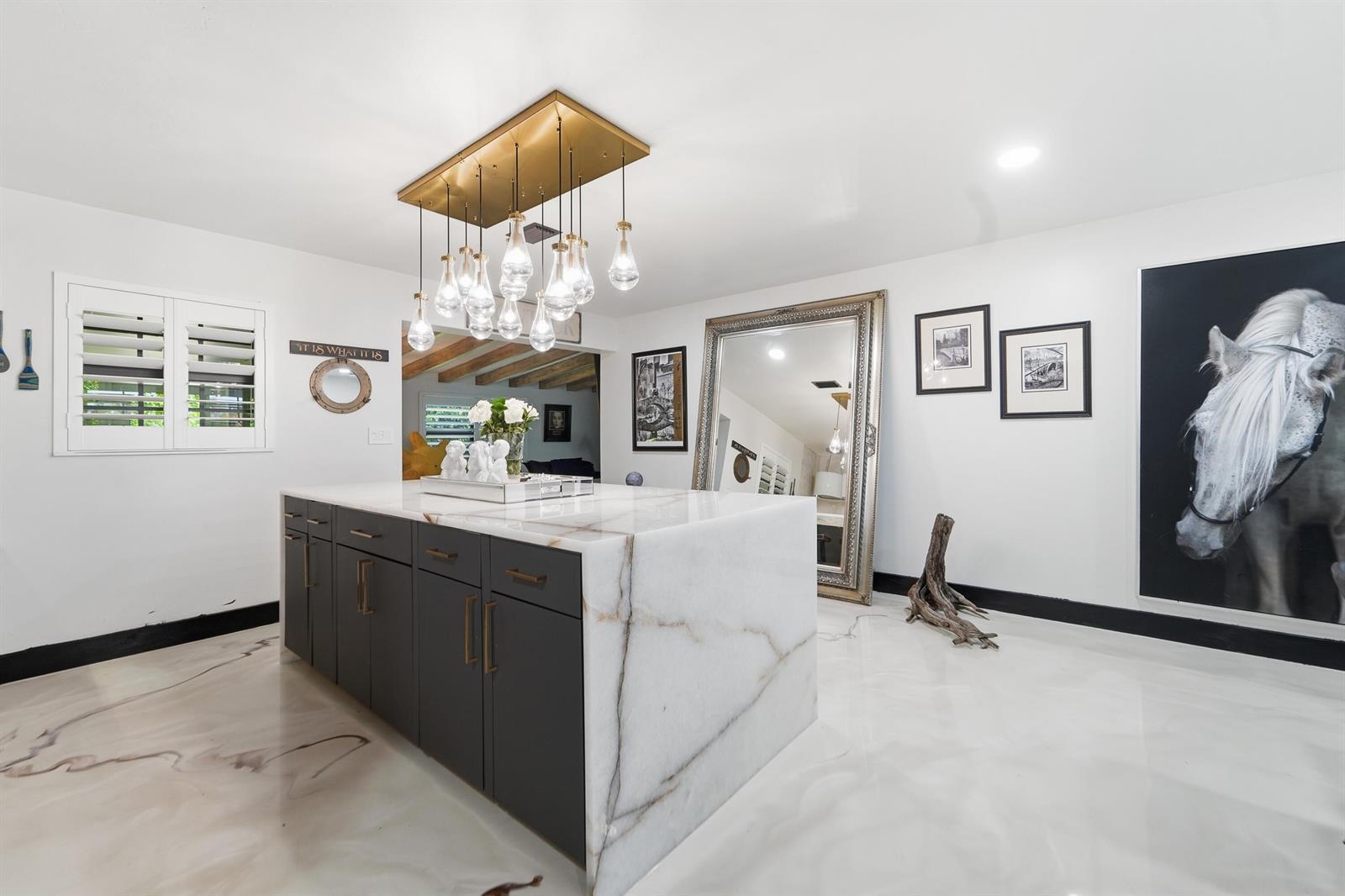 A kitchen island with a marble waterfall countertop sits in a room with white floors — 722 Greenbriar Drive, Lake Park FL 33403, LAKE PARK, FL